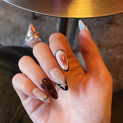 Hand with brown nail set featuring print designs of leopard spots, zebra-patterned, French tips and aura design