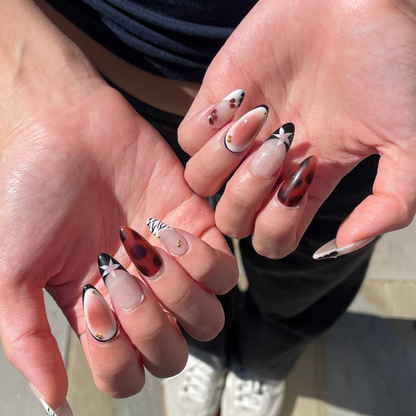 Two hands with brown nail set featuring print designs of leopard spots, zebra-patterned, French tips and aura design