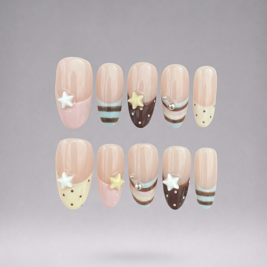 Ten false press-on nails arranged in two rows against a soft gray gradient background. The nails feature a nude beige base with pastel pink tips, decorative white stars, yellow stars, brown stripes, and light blue stripes.